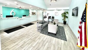 Un espace d’accueil moderne avec un mur d’accent de couleur turquoise, un comptoir d’accueil, un canapé gris, une table basse et un grand drapeau américain.