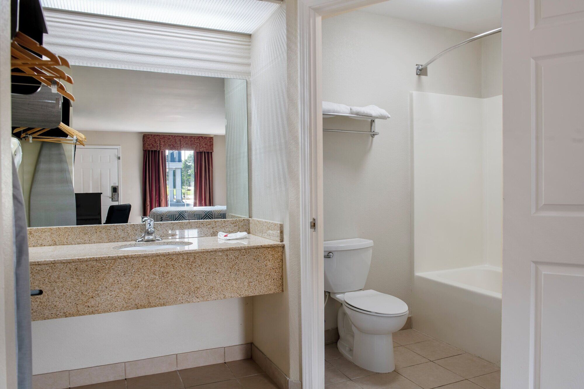 A bathroom with a granite countertop sink, a toilet, and a shower.