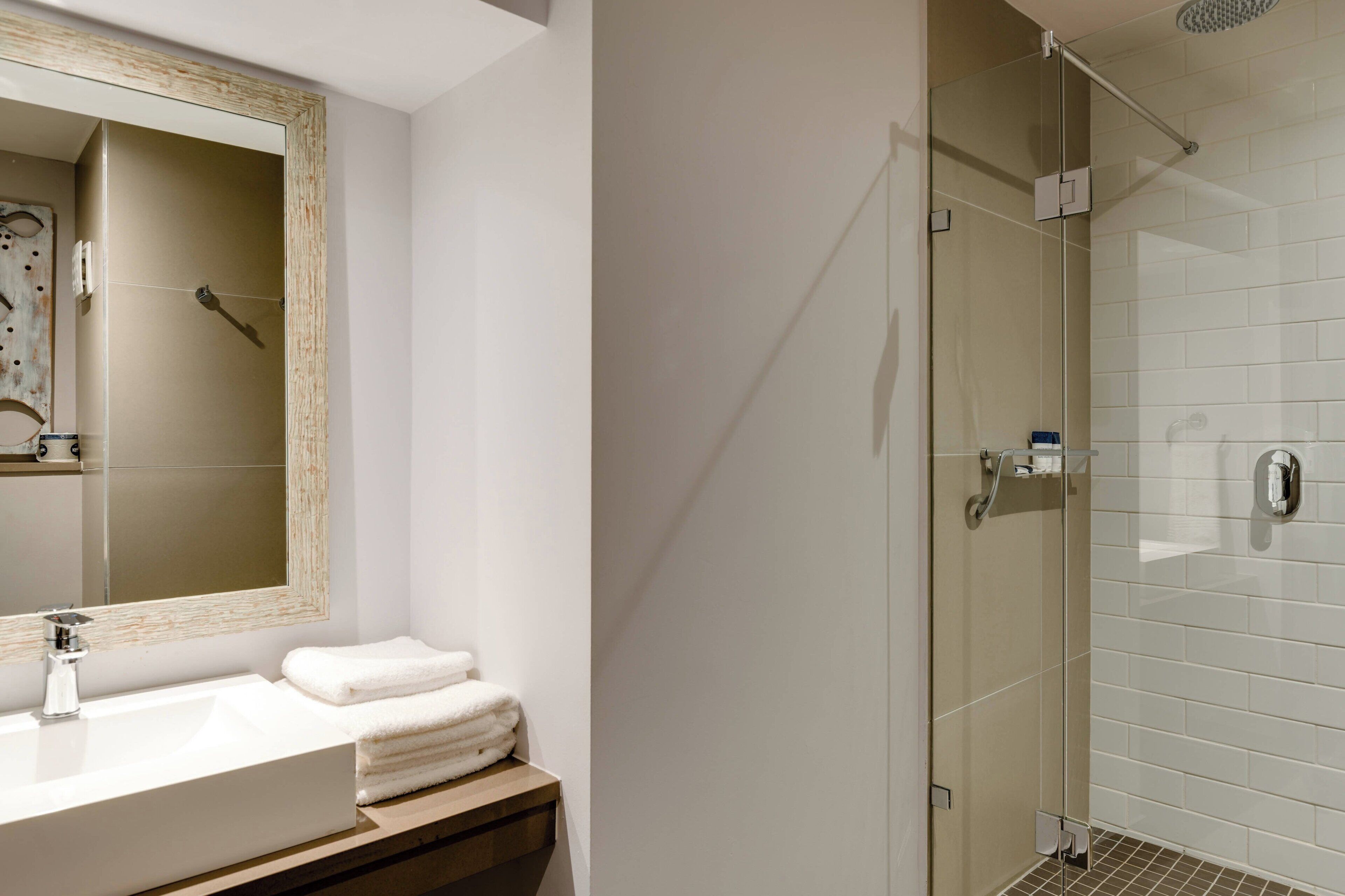 Un bagno moderno con uno specchio grande, un lavandino e una cabina doccia in vetro.