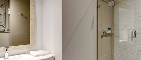 Une salle de bain moderne avec un grand miroir, un lavabo et une douche à parois de verre.