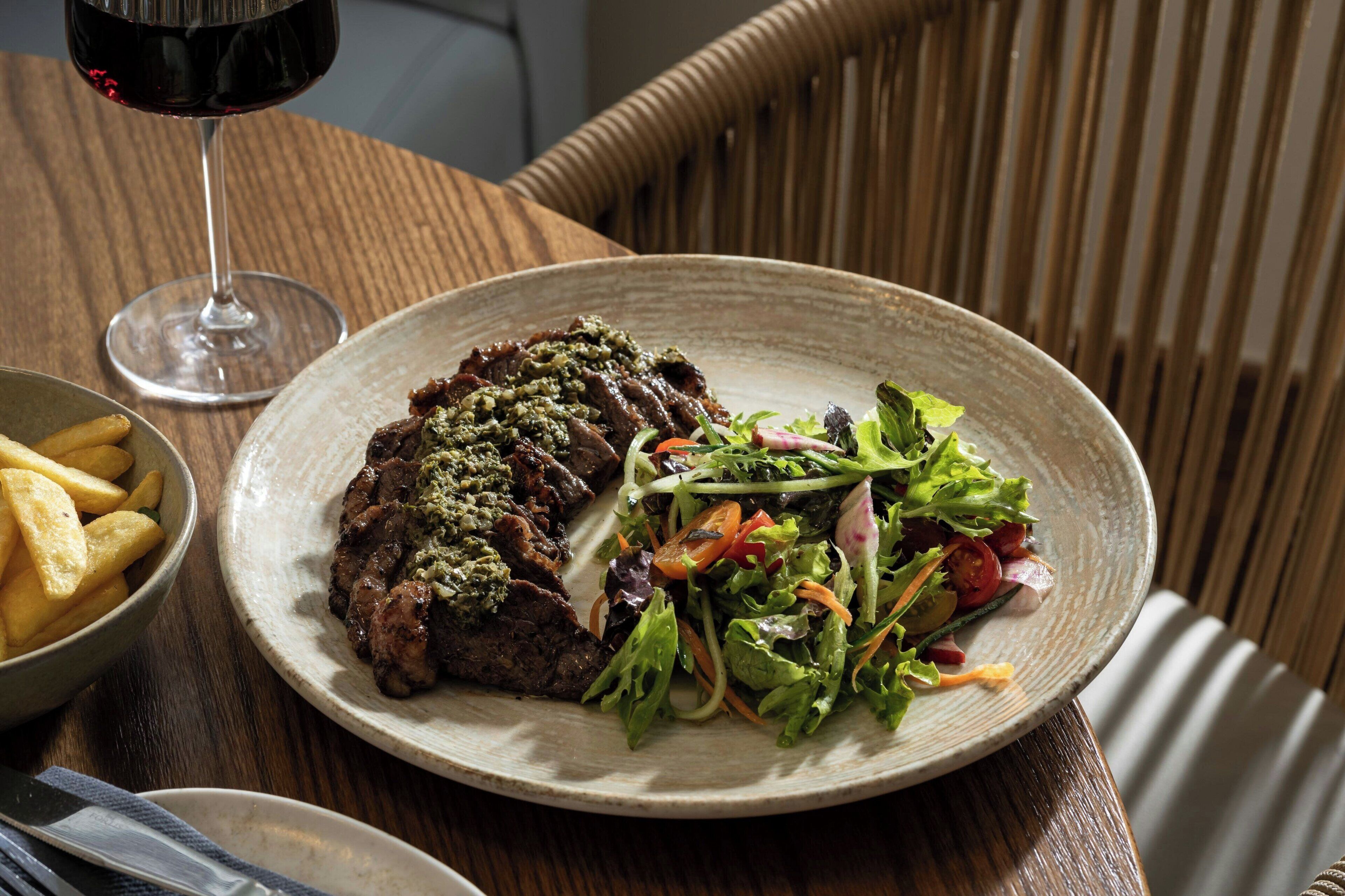 A plate of food with a glass of red wine on a wooden table.