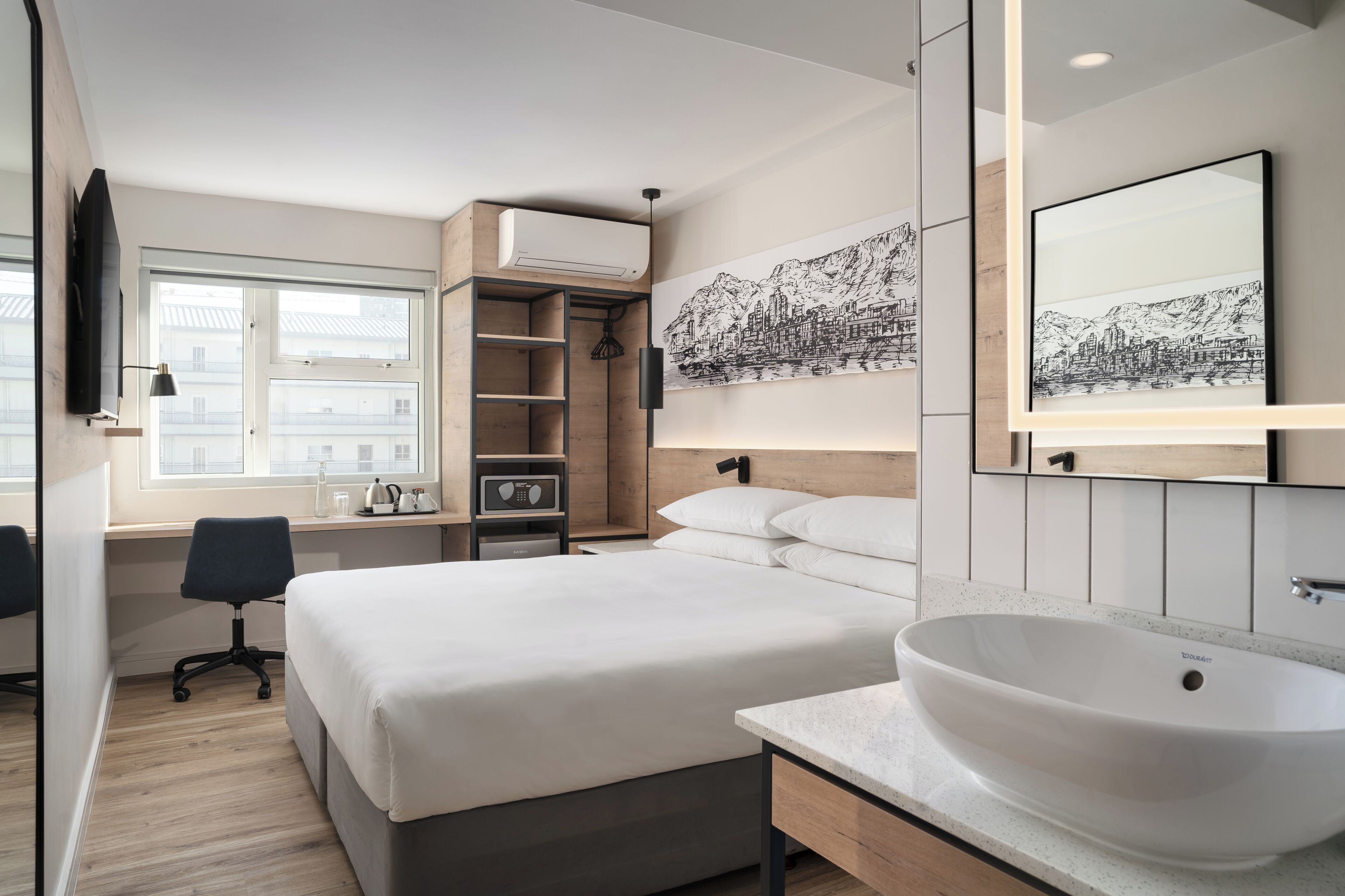A modern bedroom with a bed, bedside table, and a large window.