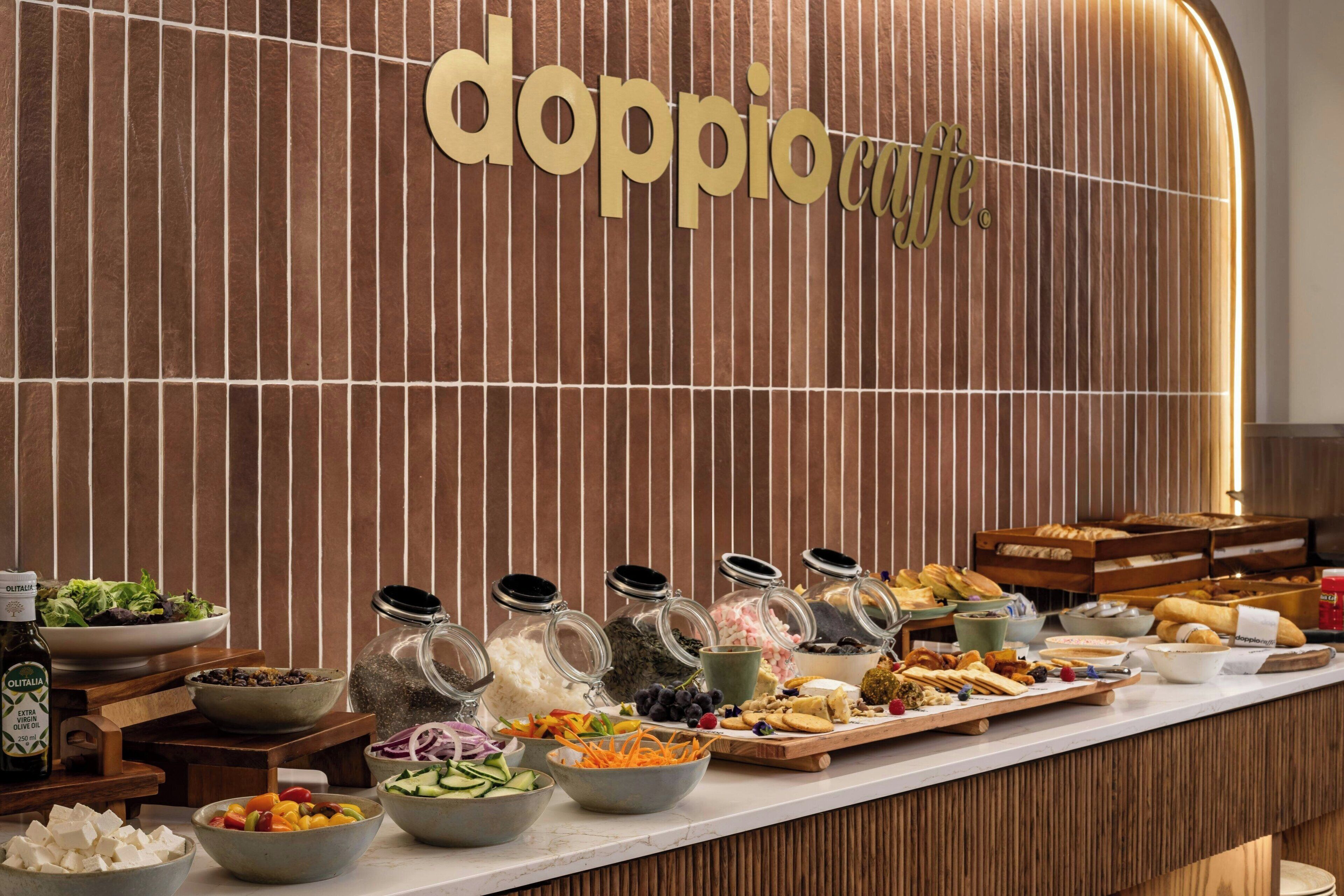 A buffet setup with various food items and a sign that reads "doppio cafe".