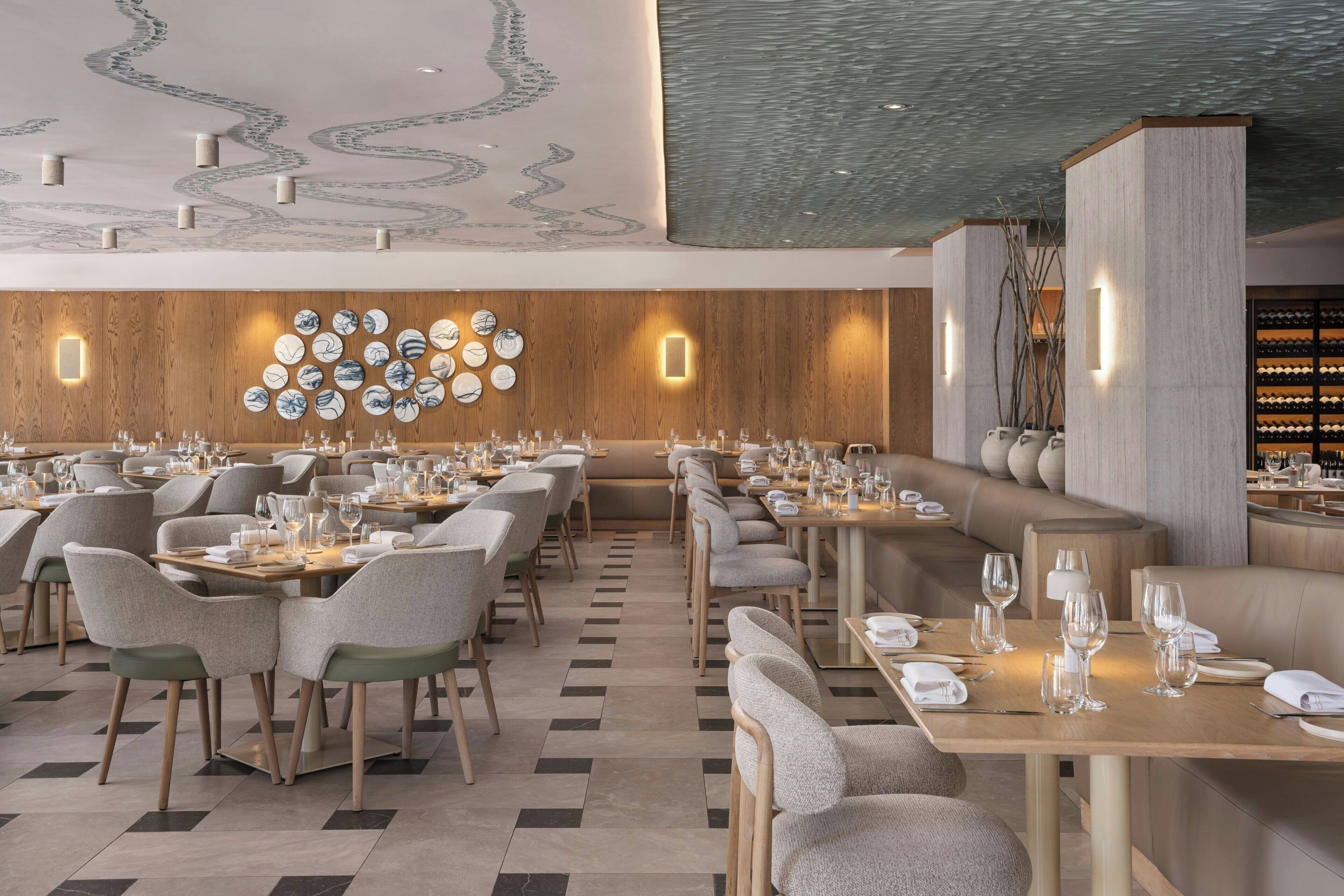 Um restaurante moderno com um balcão comprido, diversas áreas de estar e um design decorativo no teto.