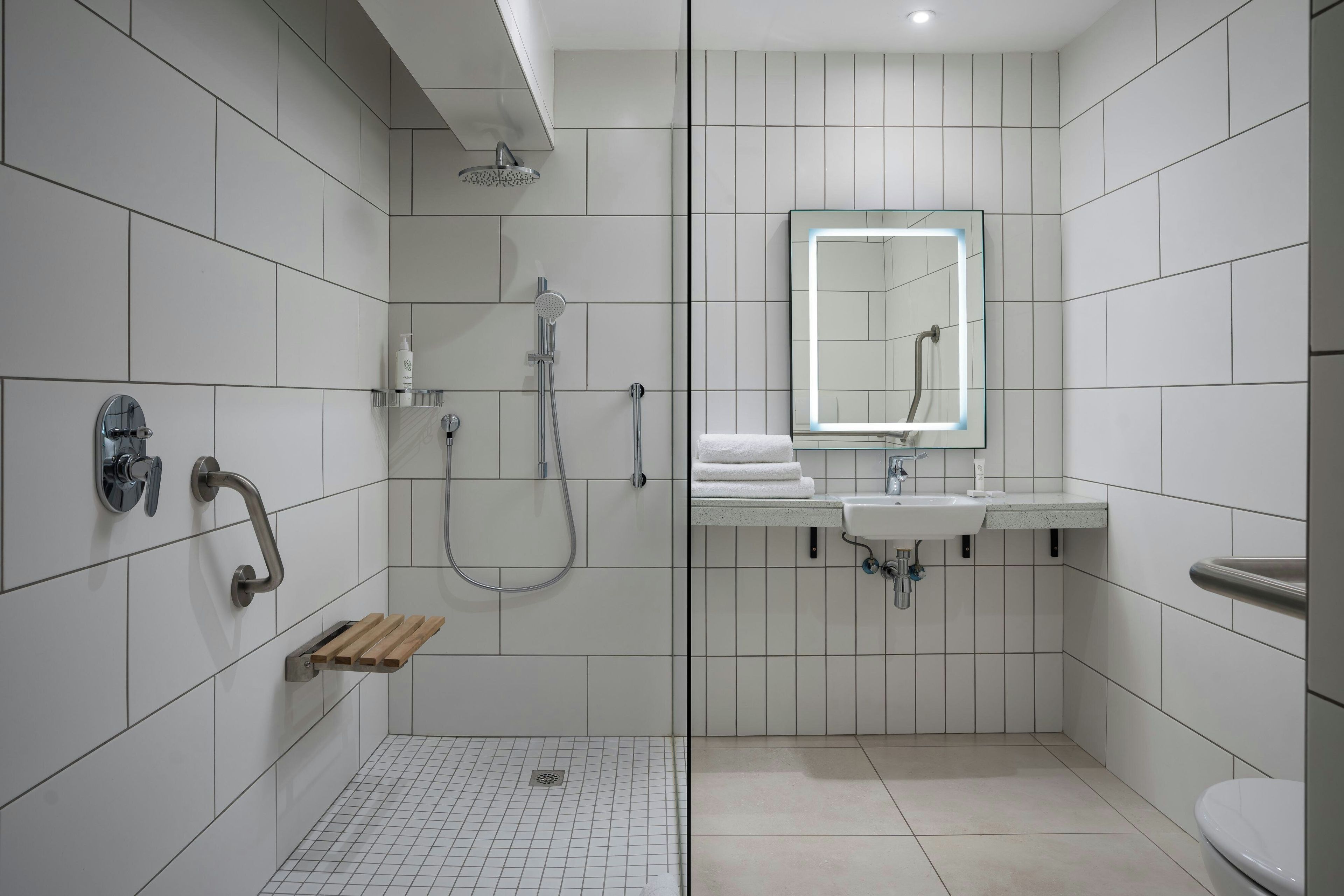 Ein modernes Badezimmer mit begehbarer Dusche, einem Glastrennwand-Waschtisch mit Spiegel und Toilette.
