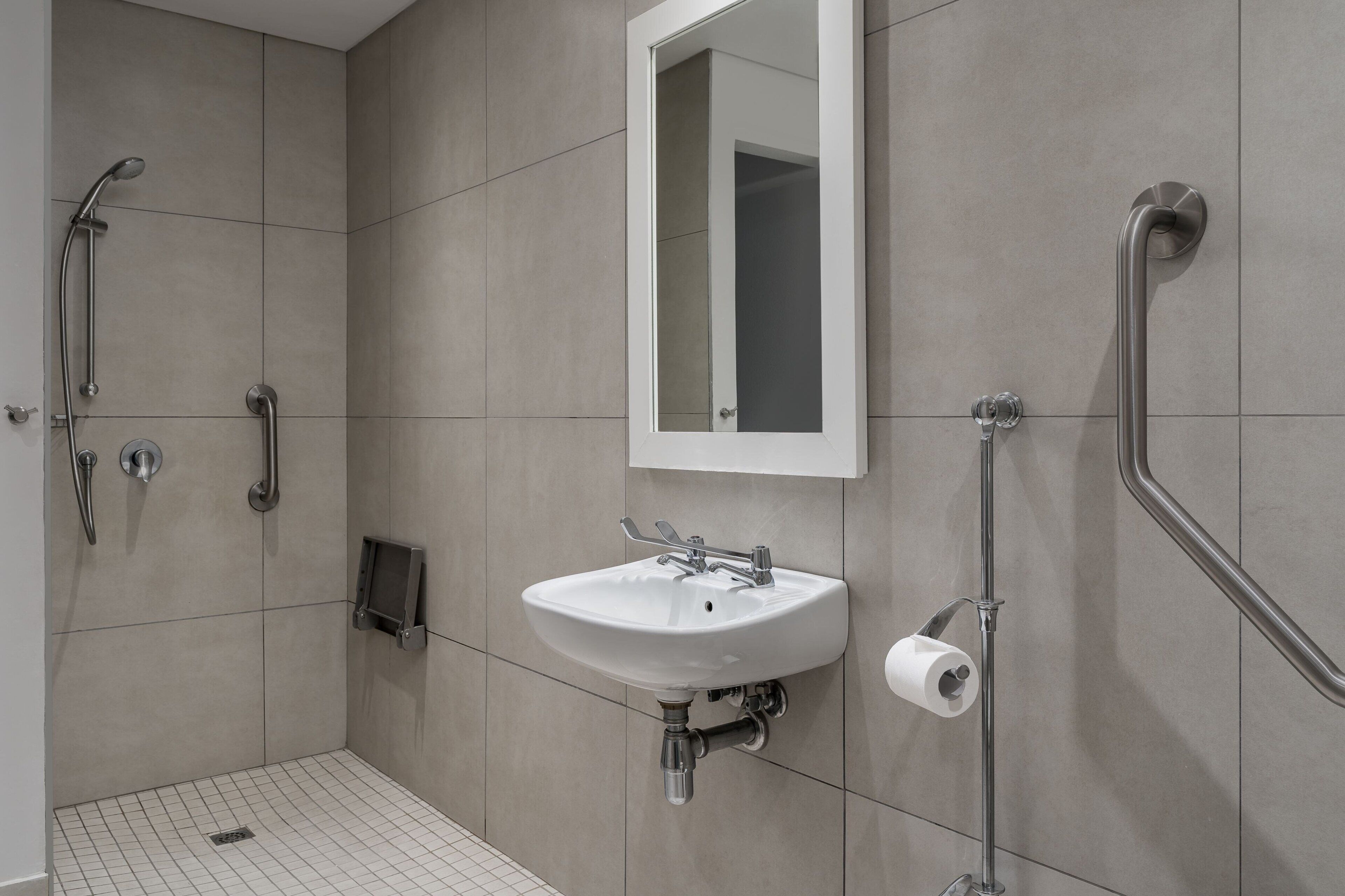 A modern bathroom with a shower, a sink, a mirror, and a toilet.