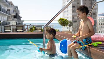 Guests can enjoy ocean views from the pool area, adjacent to a building with balconies.