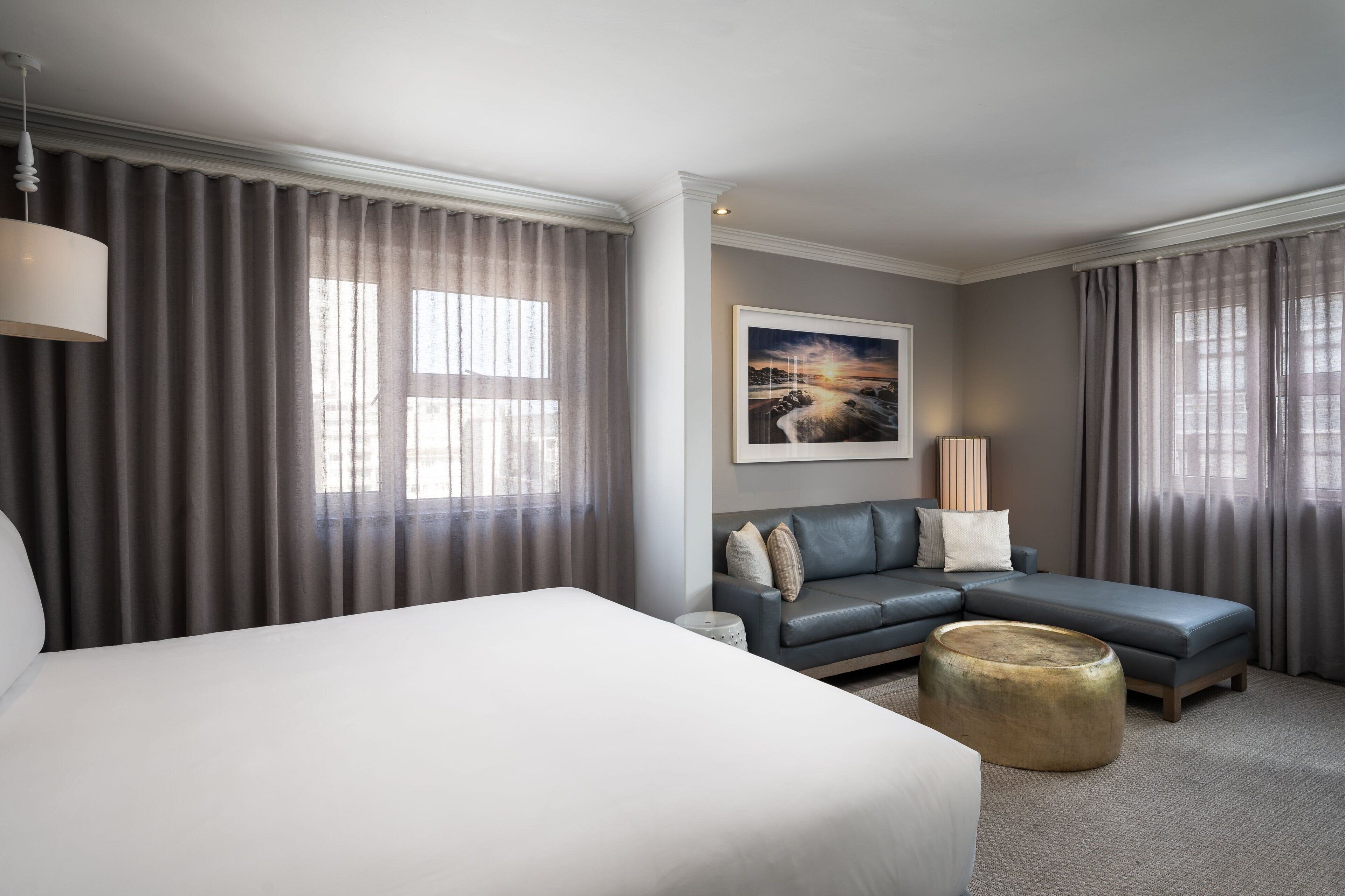 Ein Hotelzimmer mit einem großen Bett, einem Sofa, einem Couchtisch und einem Gemälde an der Wand.