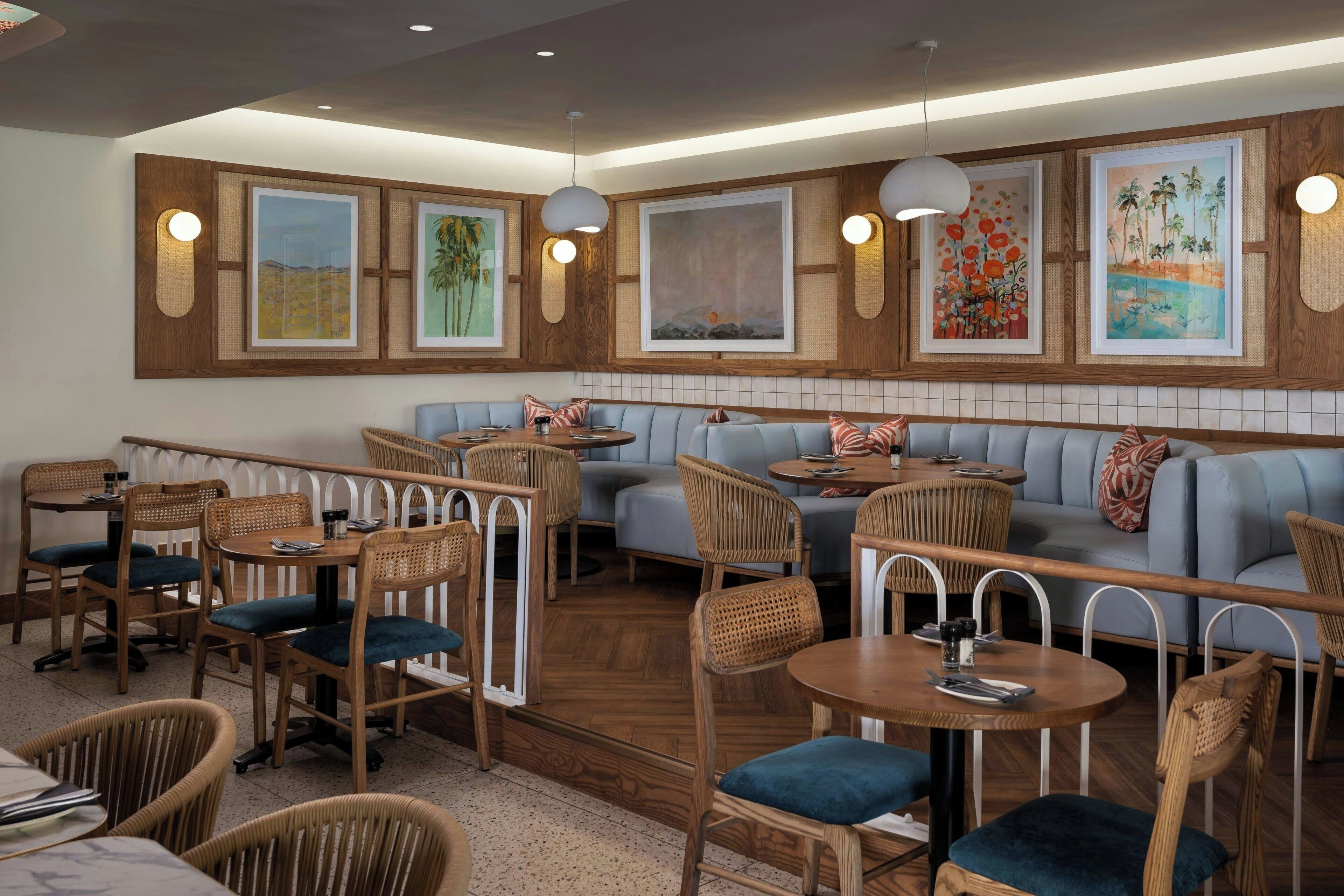 A restaurant with wooden walls, framed artwork, wicker furniture, and a blue sofa.