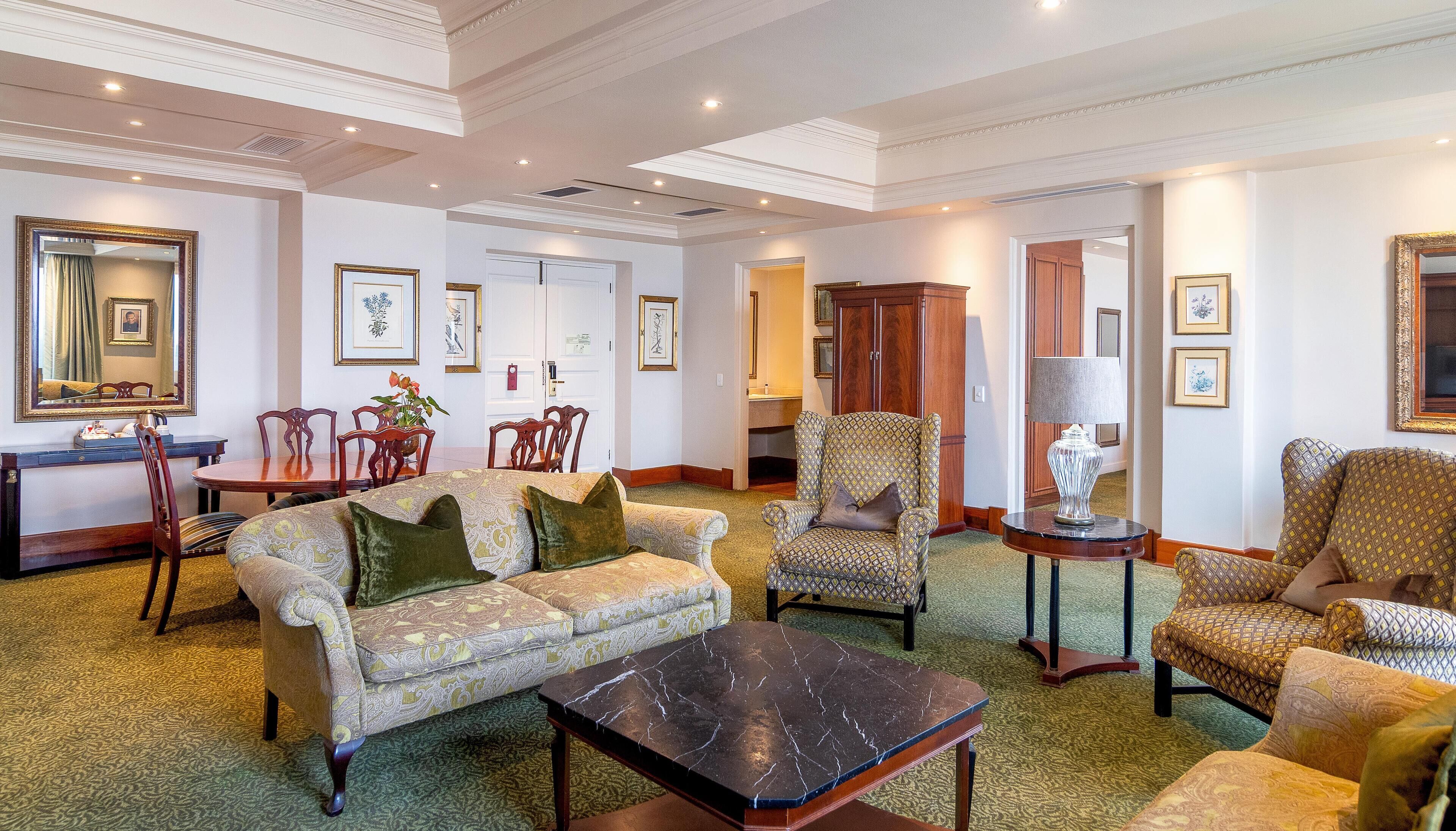 A spacious living room with a sofa, armchairs, a coffee table, and a dining area with chairs and a table.