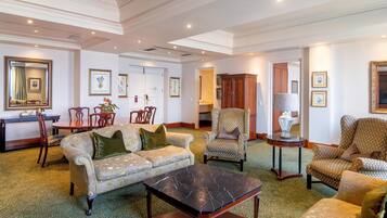A spacious living room with a sofa, armchairs, a coffee table, and a dining area with chairs and a table.