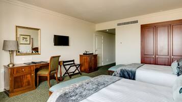A hotel room with two beds, a desk, a chair, a television, and a wardrobe.