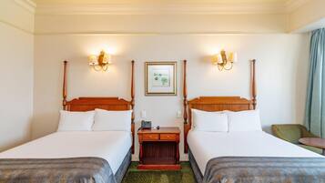 Ein Hotelzimmer mit zwei Einzelbetten, einem hölzernen Nachttisch, einem gerahmten Bild an der Wand und einem grünen Teppich.