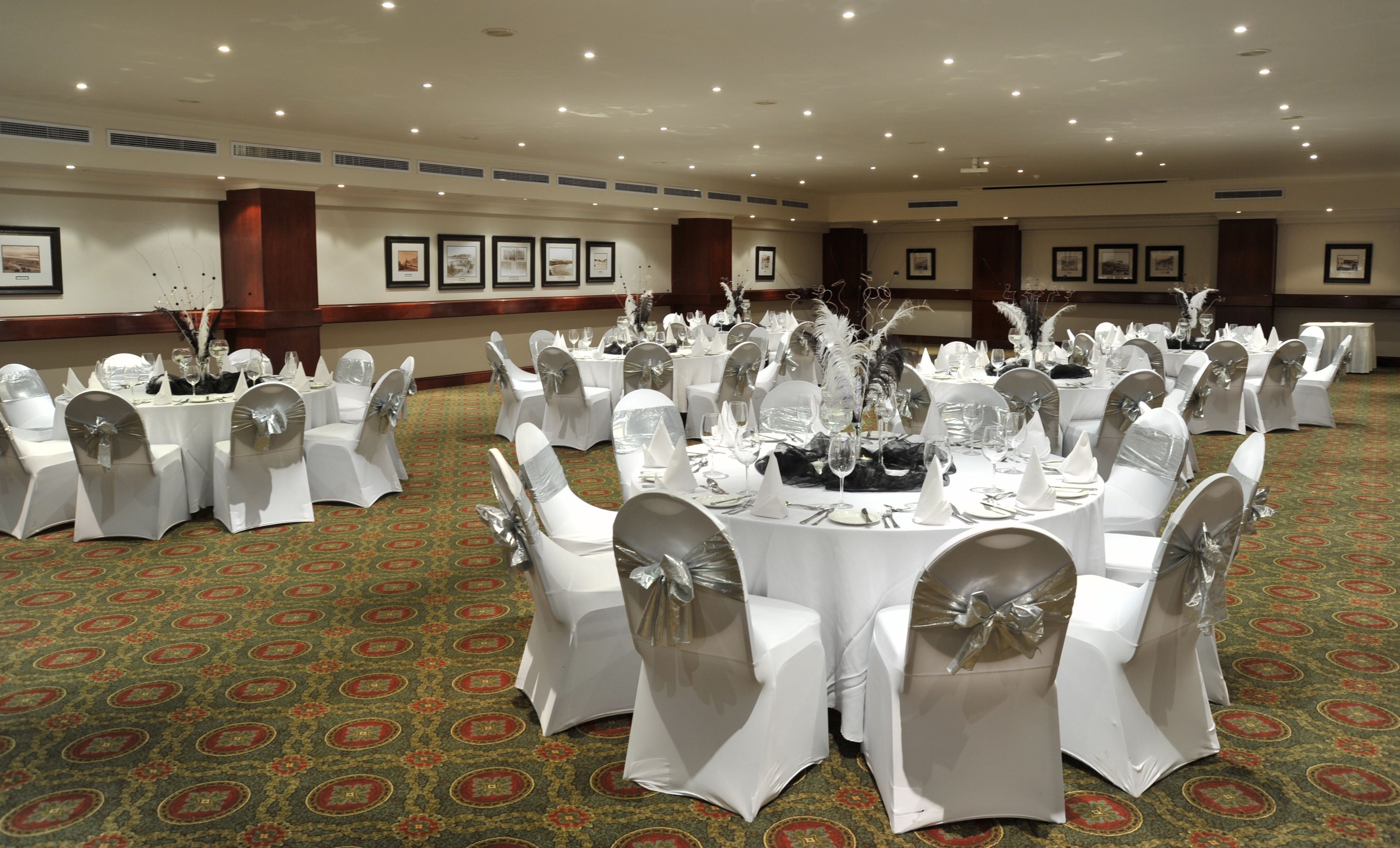 A banquet hall with round tables, white tablecloths, and chairs with silver sashes.