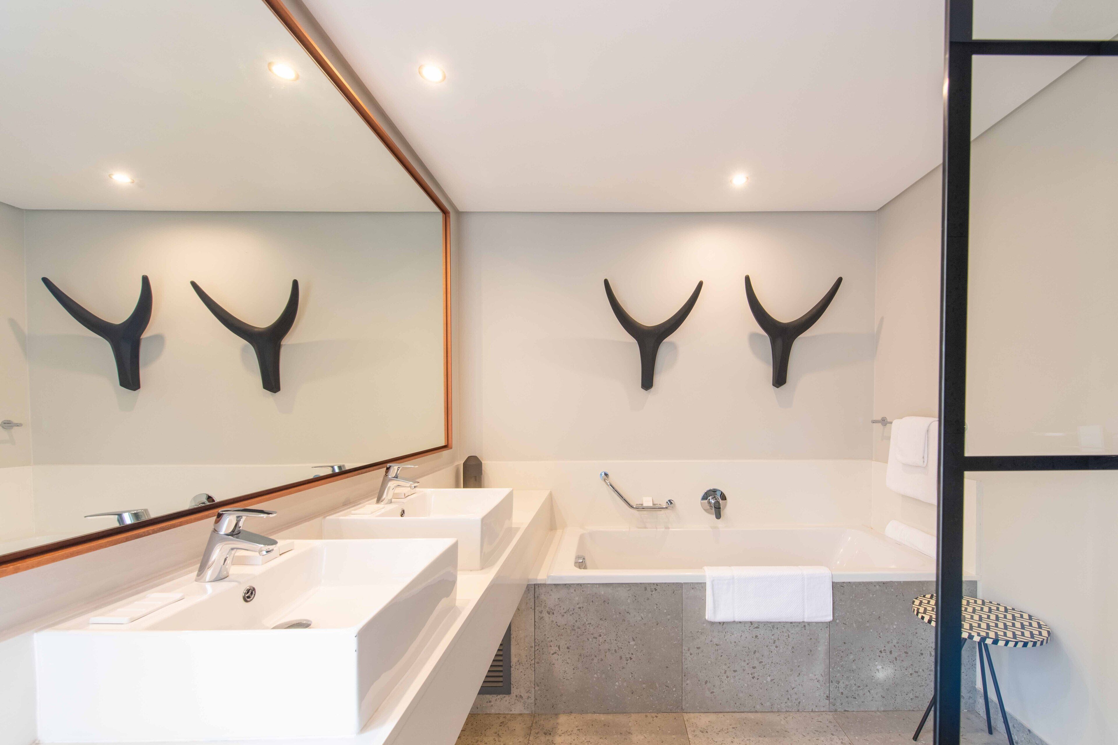 Een moderne badkamer met twee wastafels, een badkuip en een douche.