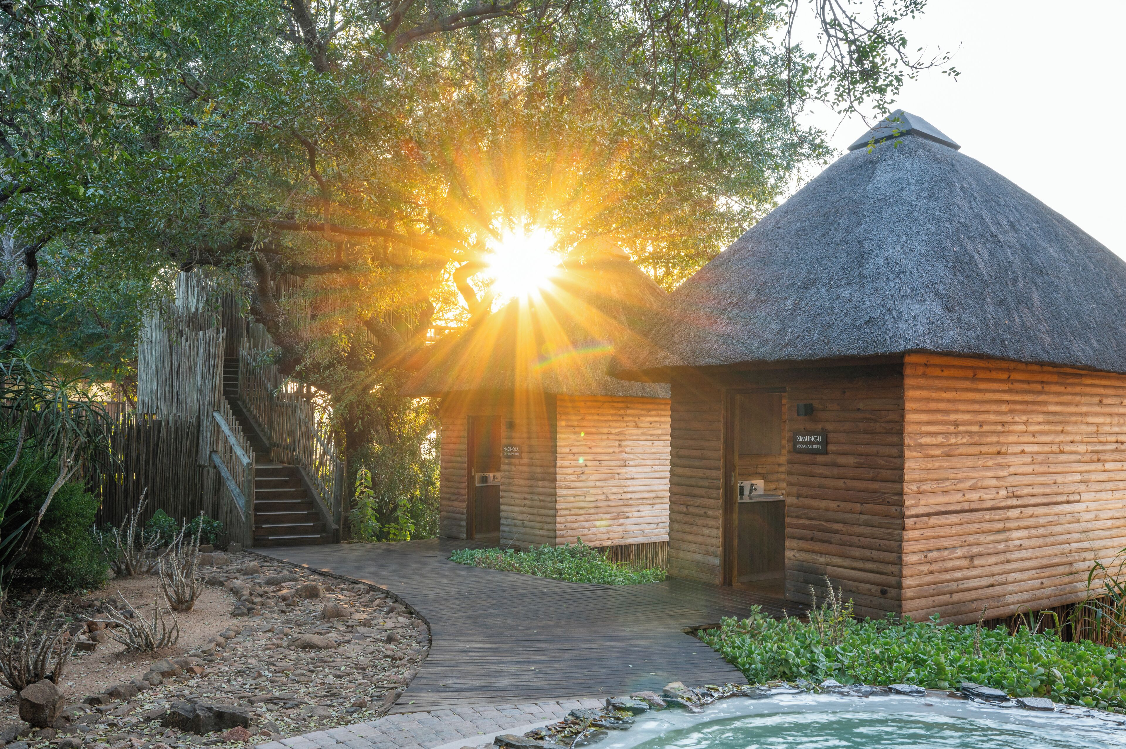 A thatched-roof building with a wooden exterior, a wooden staircase, and a sign reading "MUNGI".