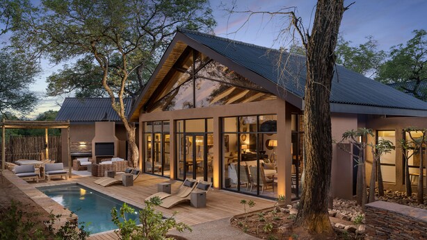 Una casa moderna con piscina, zona de estar exterior y una chimenea.
