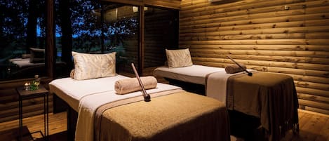 Una cabaña acogedora con dos camas, una mesita y un ventanal grande con vistas al exterior.