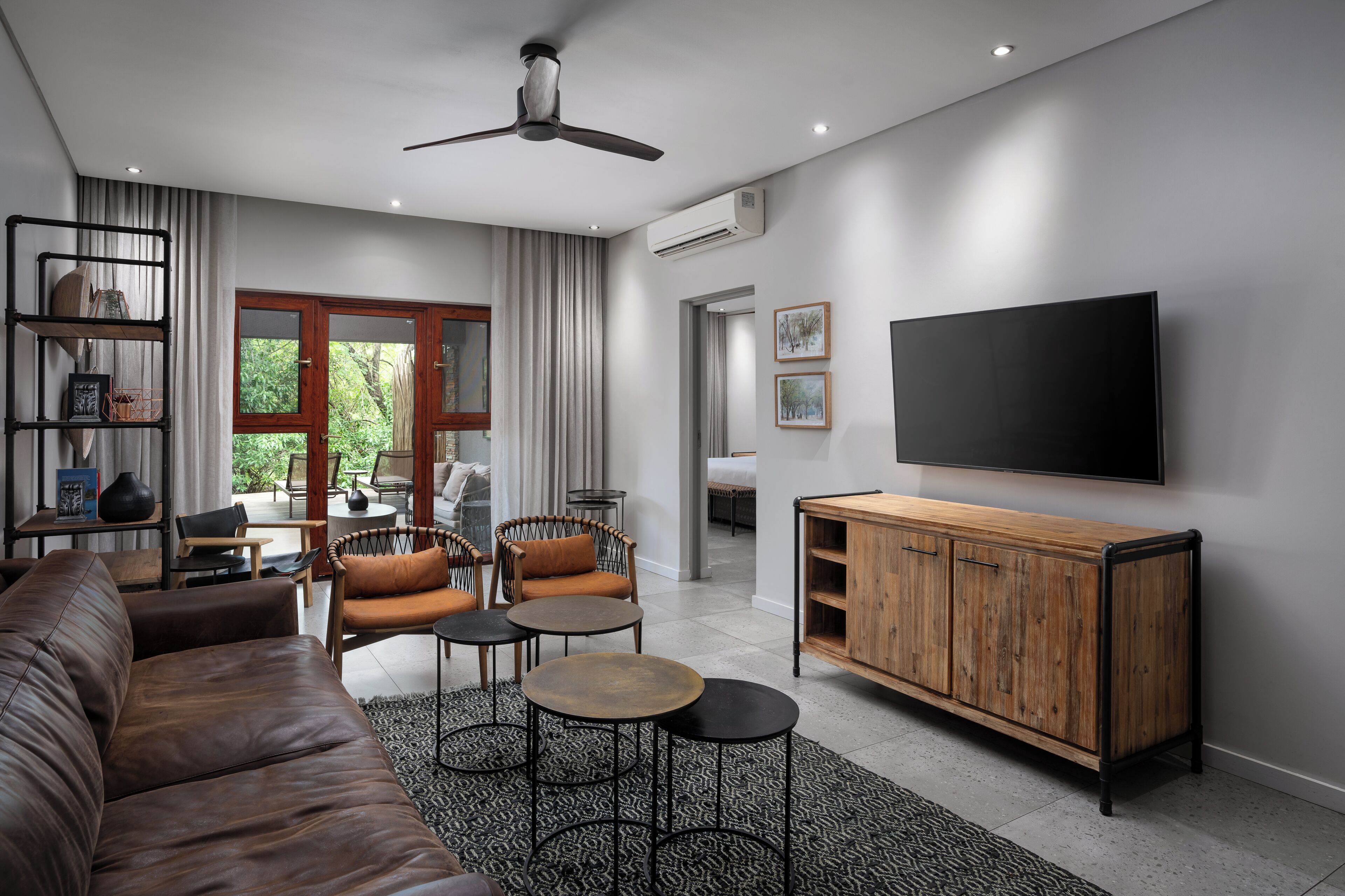 A modern living room with a leather sofa, wooden coffee table, and a TV mounted on the wall.