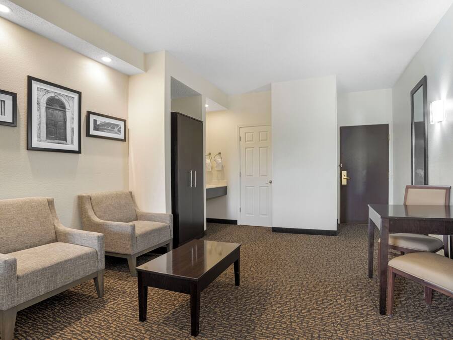 Un vestíbulo de hotel con mostrador de recepción, dos sofás, una mesa de centro y una mesa de comedor con sillas.