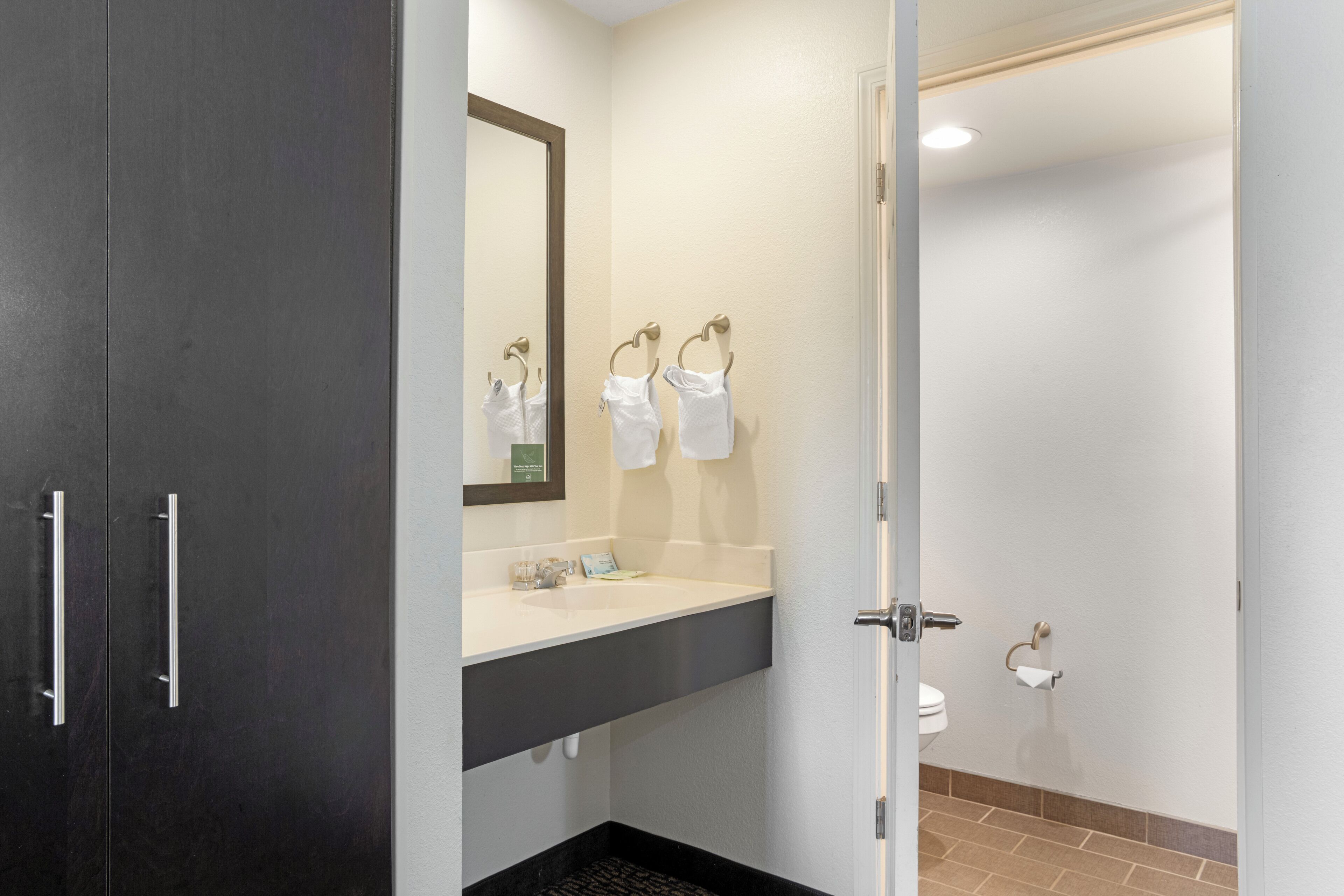 A modern bathroom with a dark vanity, a white sink, and a mirror.