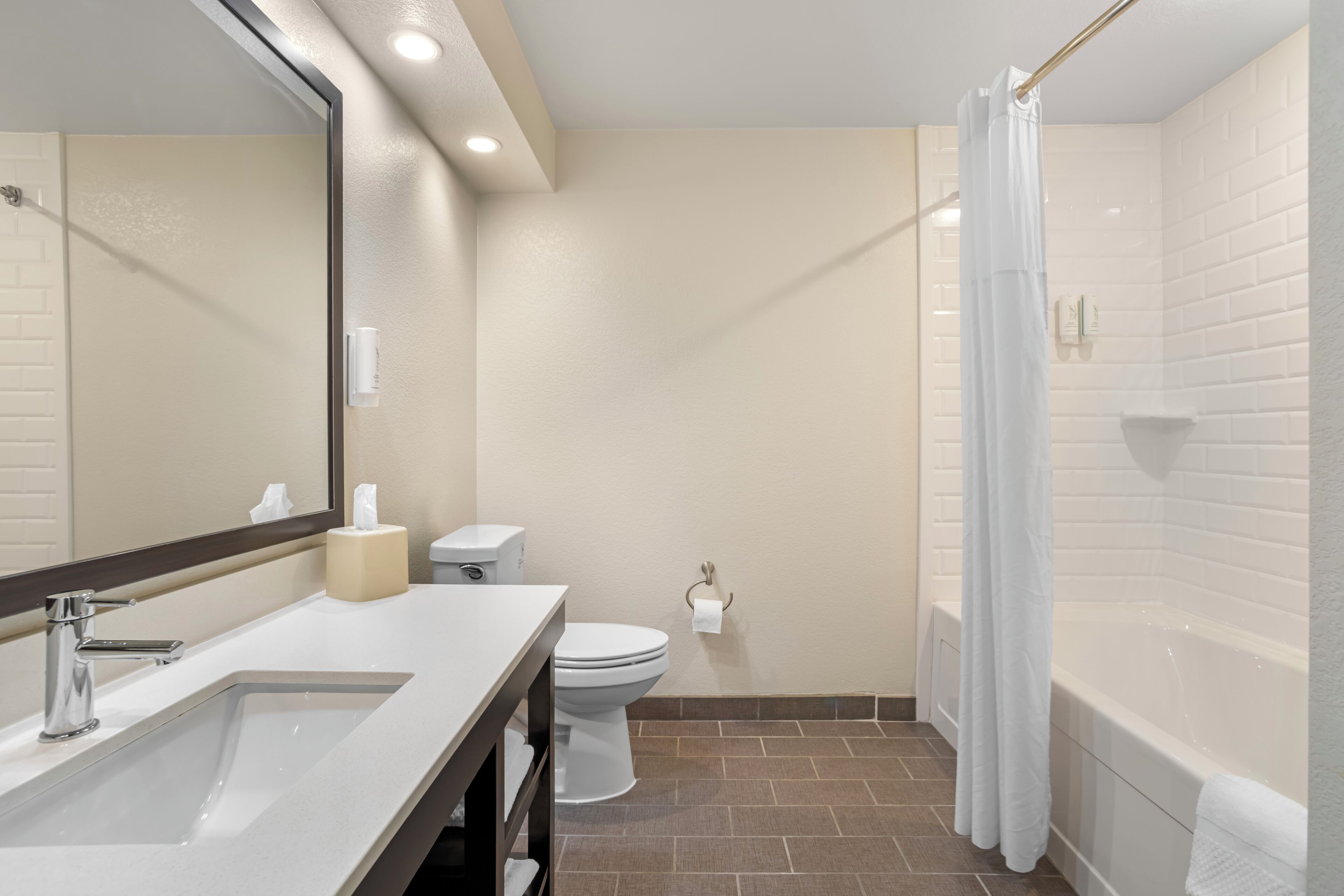 A bathroom with a sink, mirror, toilet, and bathtub.