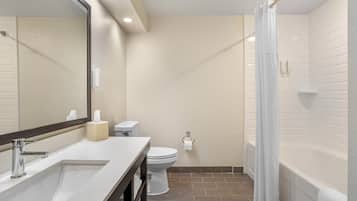A bathroom with a sink, mirror, toilet, and bathtub.