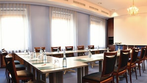 A conference room with a long table, chairs, a projector screen, and a whiteboard. - Hotel Amberger (Würzburg)