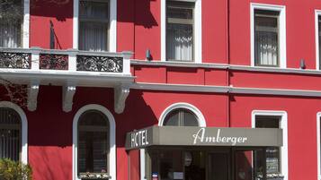 Ein rotes Gebäude mit einem Hotelschild, auf dem "Hotel Amberger" steht.