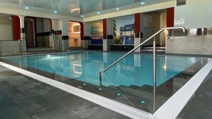 An indoor swimming pool with clear water, surrounded by a tiled floor and a glass barrier. -  Hotel Ritter Badenweiler (Badenweiler)