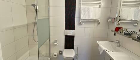 A bathroom with a glass shower enclosure, a toilet, and two sinks with mirrors.