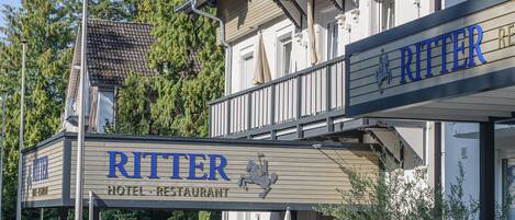 A hotel named Ritter with a signboard, outdoor seating area, and potted plants.