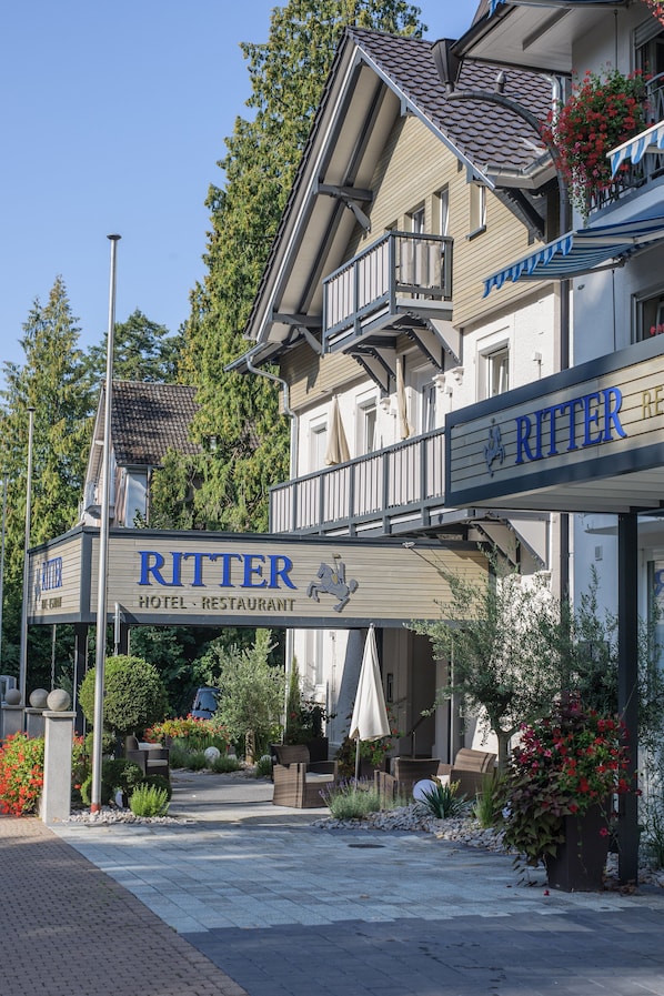 A hotel named Ritter with a signboard, outdoor seating area, and potted plants.