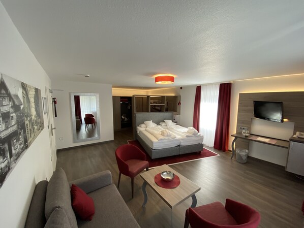 A modern hotel room with a bed, a sofa, a dining table, and a TV. - Hotel Ritter Badenweiler (Badenweiler)