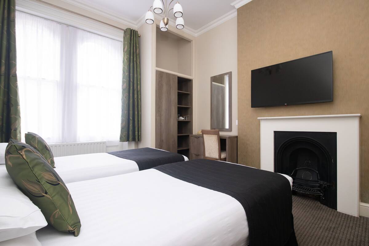 Habitación de hotel con dos camas, televisión, chimenea y armario.