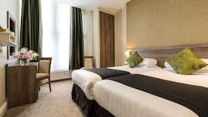 A hotel room with two beds, a desk, a chair, and a large window with curtains. - Kensington Gardens Hotel (London)
