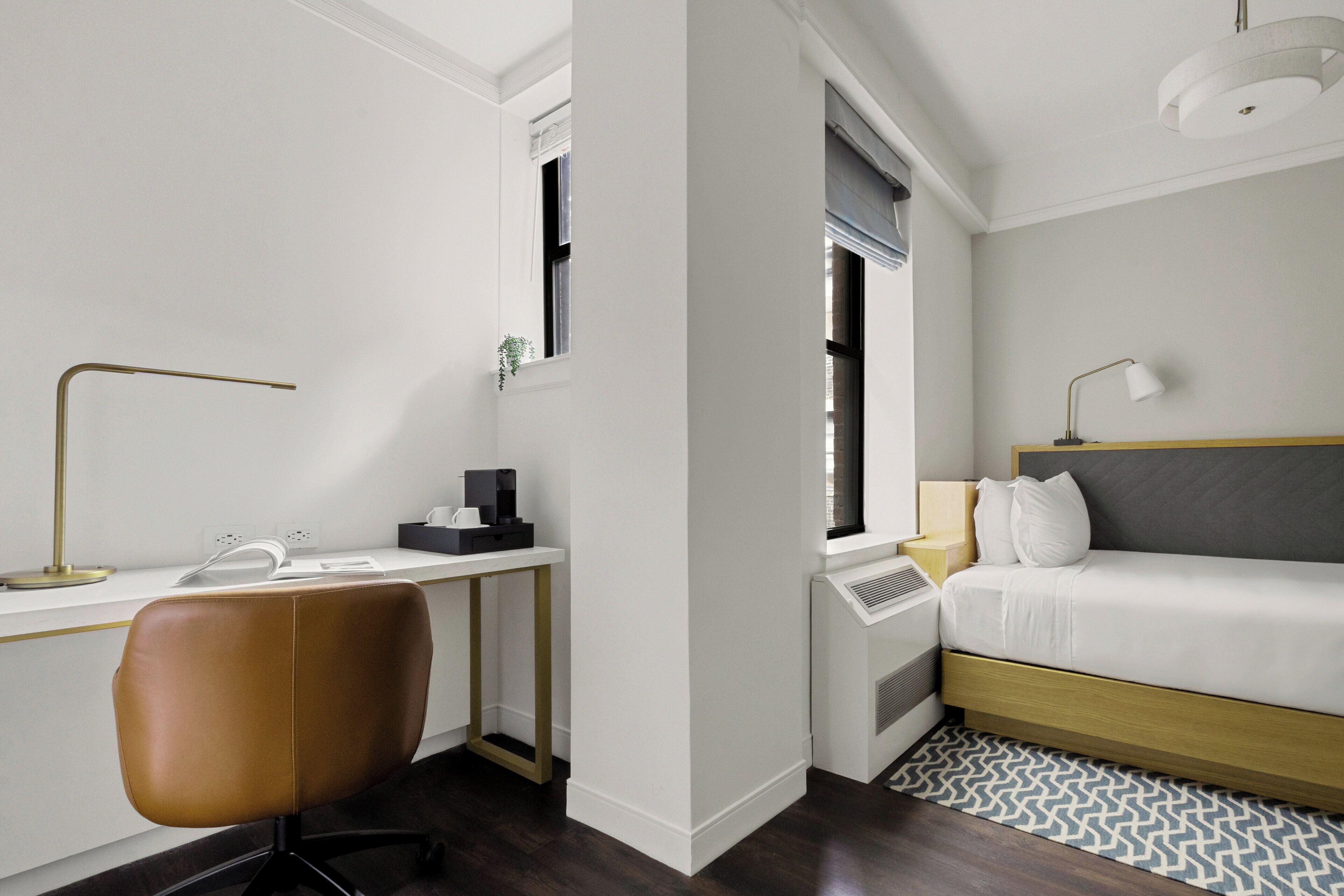 Una habitación de hotel moderna con escritorio, silla y cama con cabecera.