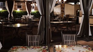 Un espace de restauration en plein air, avec des tables et des chaises, des rideaux et un lustre.