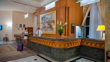 A reception area with a marble counter, a large painting, and a reception desk.