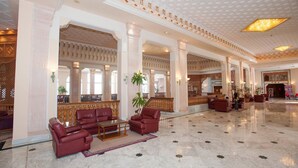 A spacious lobby with marble flooring, red leather seating, and a high ceiling with decorative patterns. - Mahdia Palace Thalasso (Mahdia)