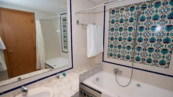 A bathroom with a marble sink, a bathtub, and a shower.