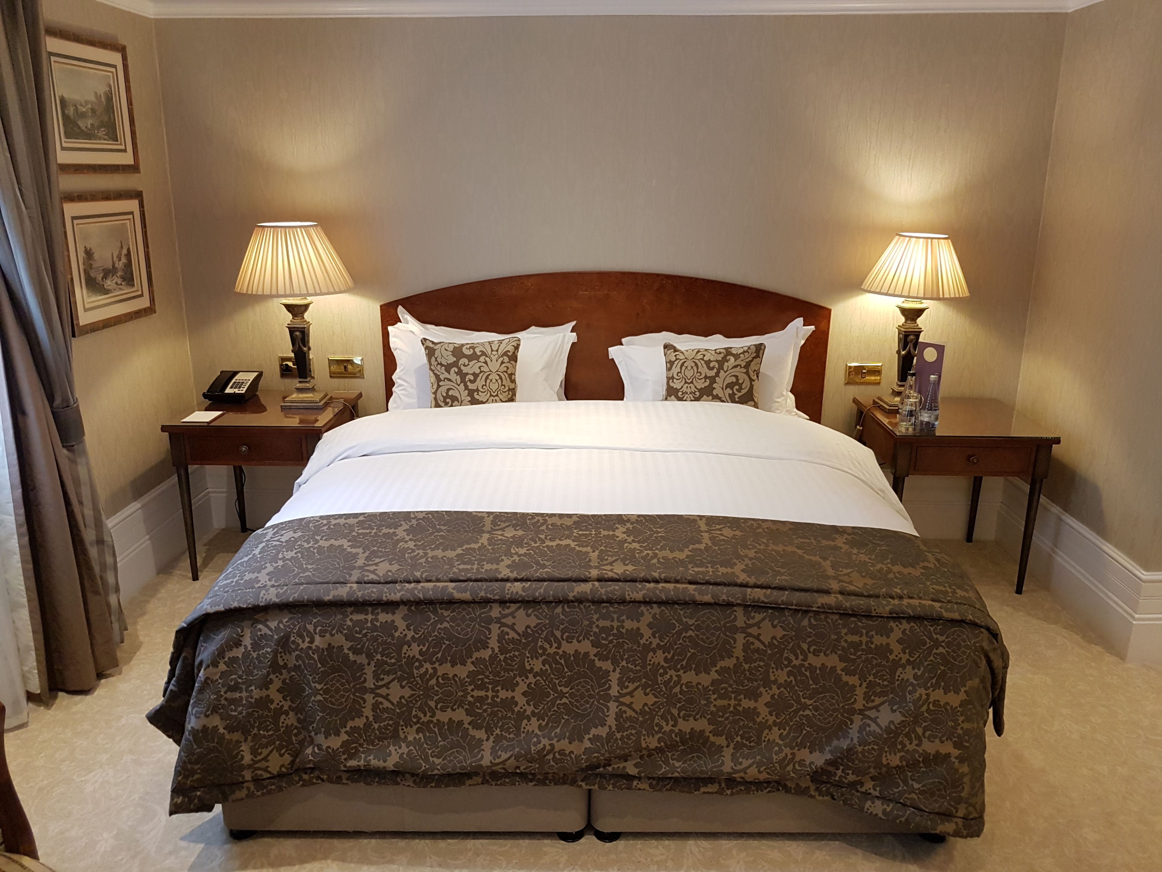 Une chambre d’hôtel avec un grand lit, deux tables de chevet, un téléphone et deux lampes.