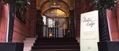 The entrance to The Porters Lodge with a signboard listing amenities like cocktails, wines, ales, specialty savouries, and afternoon teas.