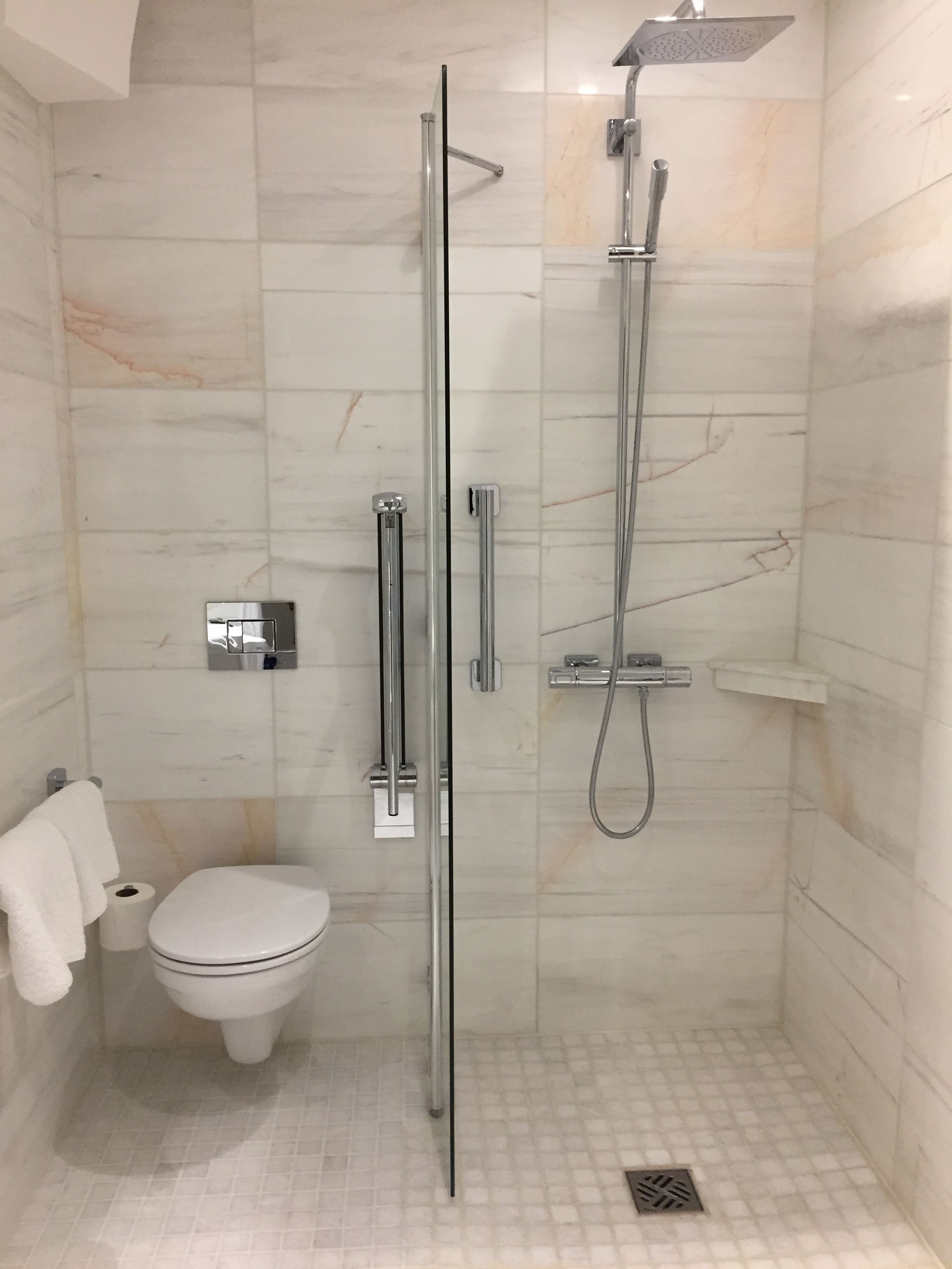A glass-enclosed shower stall with a handheld showerhead and a wall-mounted faucet.