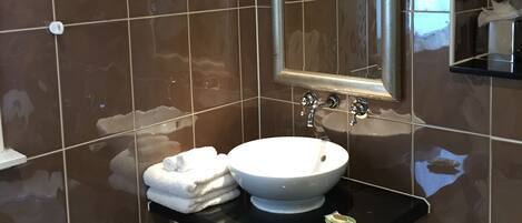 A bathroom with a white sink, a mirror, and a black countertop.