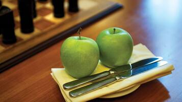 Two green apples on a napkin with a knife on a wooden table.
