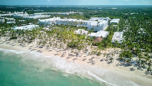 An aerial view of a resort with multiple buildings, a beach, and palm trees. - Hotel Riu Palace Macao - Adults Only - All Inclusive (Punta Cana)
