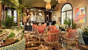 A bar area with wicker furniture, a bar counter, and a large window. - Hotel Riu Palace Macao - Adults Only - All Inclusive (Punta Cana)