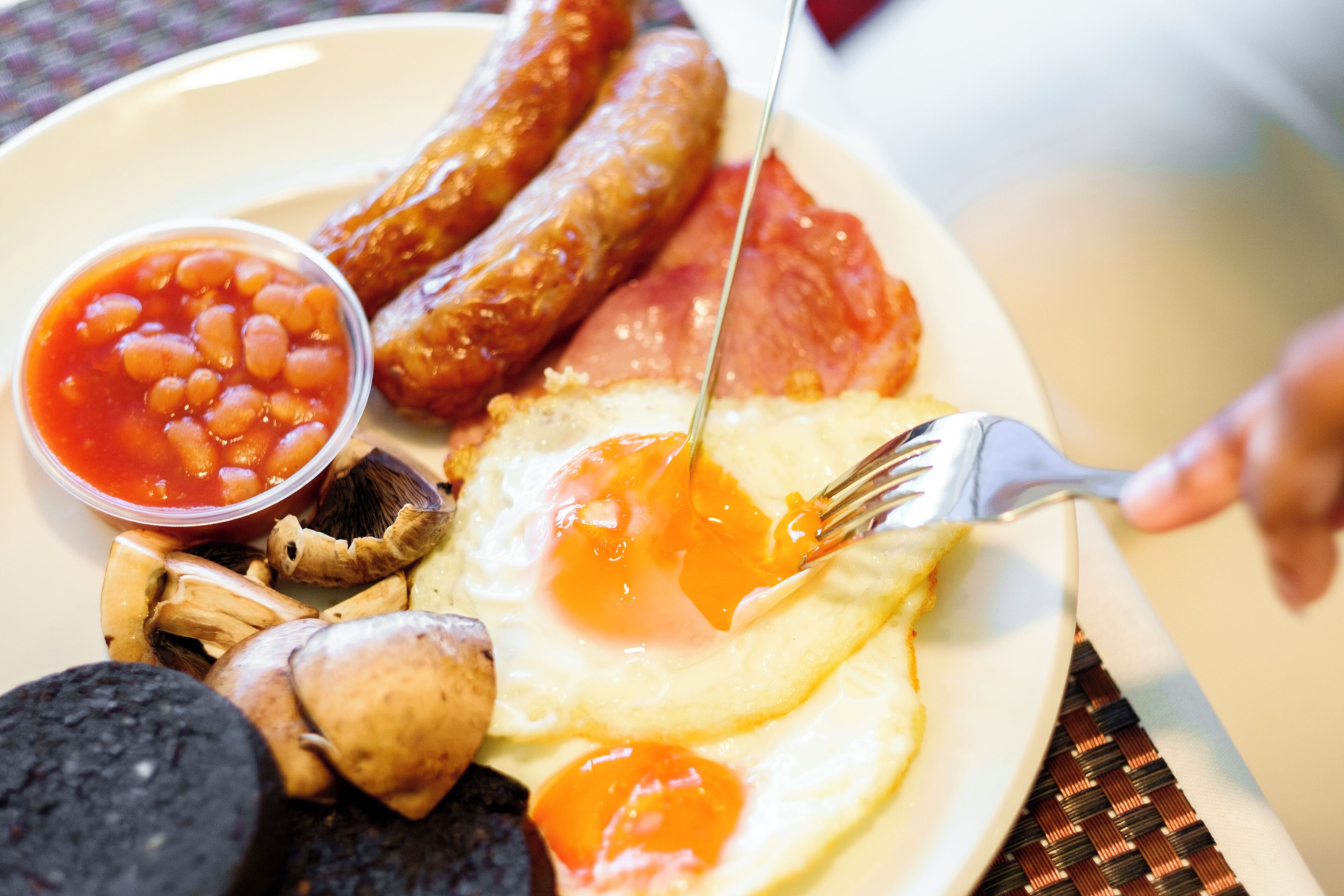 A plate with sausages, eggs, beans, and mushrooms.
