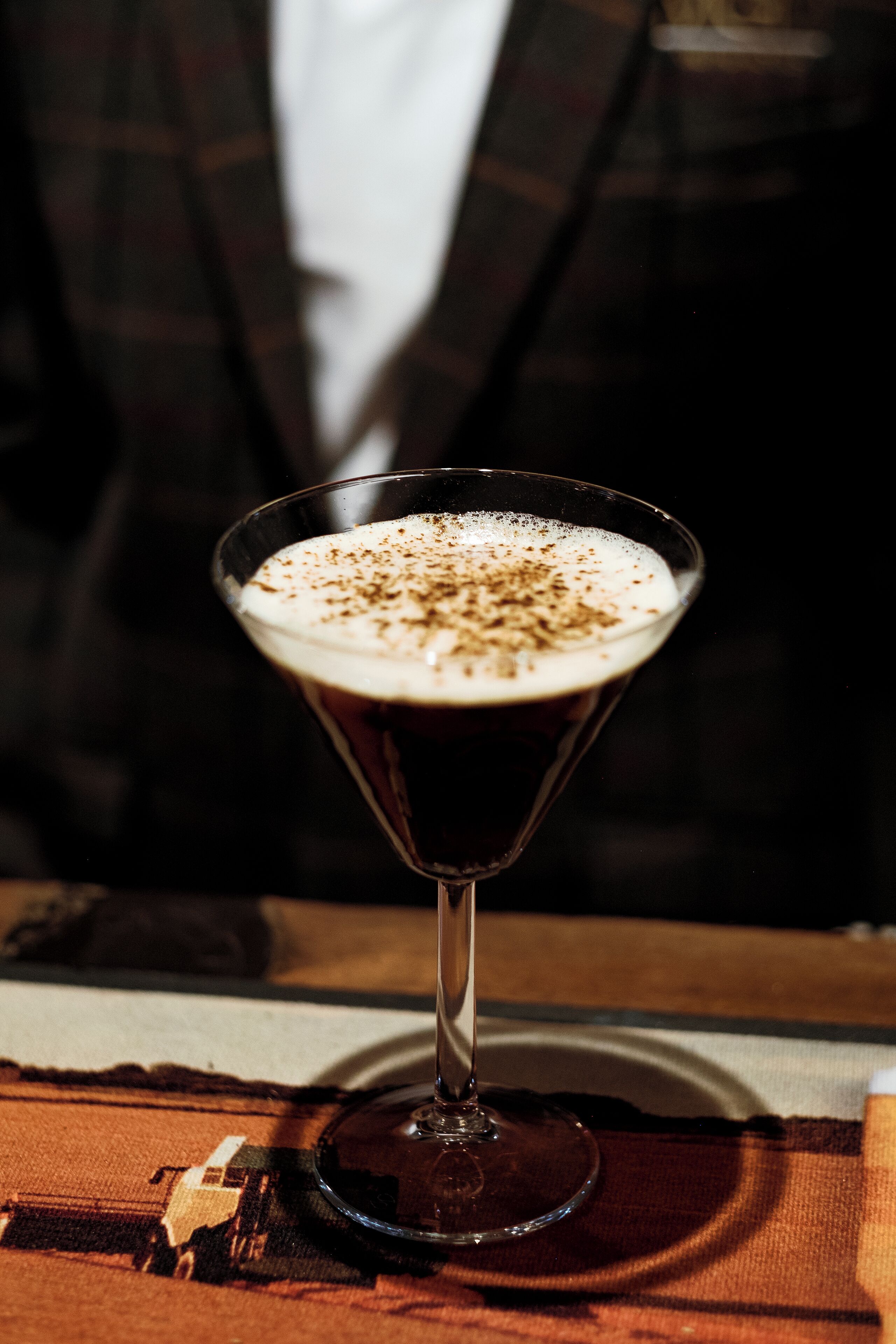 A martini glass with a frothy top on a wooden surface.